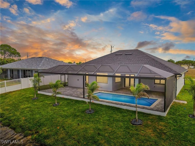 845 SW 15th Ter, Cape Coral, FL 33991 - back of property at dusk with a patio, a fenced backyard, an outdoor pool, a lawn, and glass enclosure