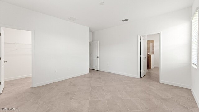 3036 Weston Manor Dr, Alva, FL 33920 - unfurnished bedroom featuring a walk in closet, multiple windows, baseboards, and visible vents