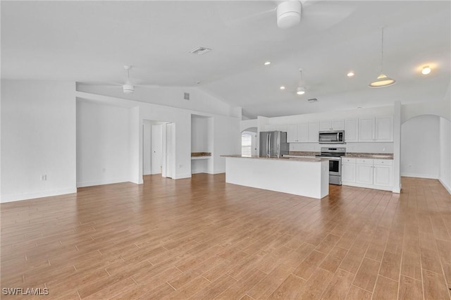 unfurnished living room with lofted ceiling, light wood-style floors, a ceiling fan, arched walkways, and baseboards