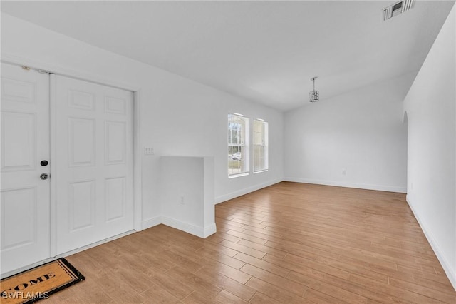 unfurnished living room with light wood-style flooring, baseboards, and lofted ceiling