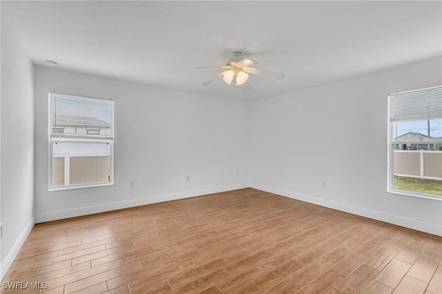 spare room with wood finished floors, a ceiling fan, and baseboards