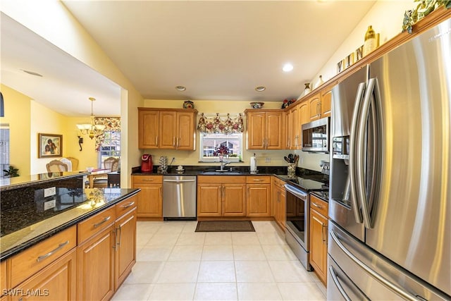kitchen featuring dark stone counters, light tile patterned floors, a healthy amount of sunlight, and stainless steel appliances