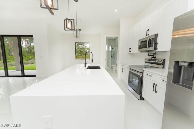 1412 5th Ave, Lehigh Acres, FL 33972 - kitchen featuring appliances with stainless steel finishes, a sink, white cabinetry, an island with sink, and hanging light fixtures