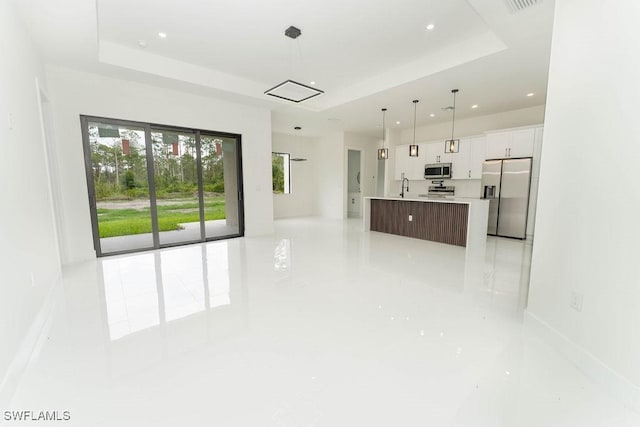 1412 5th Ave, Lehigh Acres, FL 33972 - unfurnished living room featuring a raised ceiling, recessed lighting, a sink, and baseboards