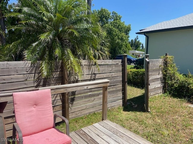 wooden terrace featuring a lawn and fence