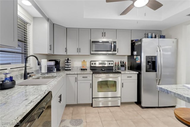 3720 SE 10th Ave Unit 102, Cape Coral, FL 33904 - kitchen featuring light tile patterned flooring, a tray ceiling, light stone counters, a sink, and stainless steel appliances