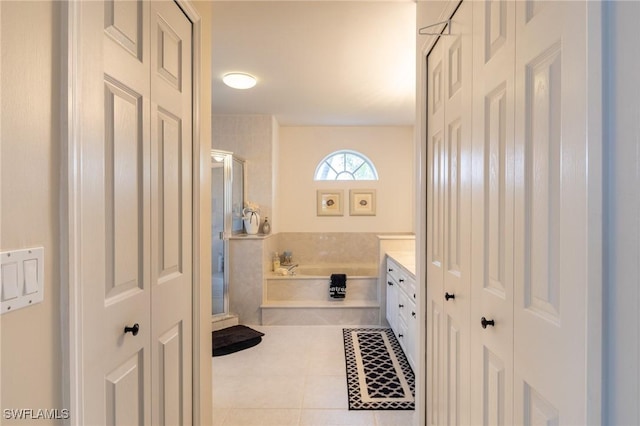 full bathroom featuring a closet, vanity, tile patterned floors, a bath, and a stall shower