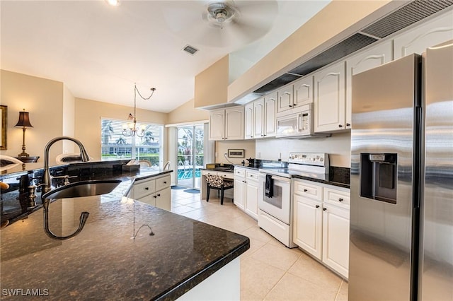 kitchen with lofted ceiling, white appliances, white cabinets, a sink, and light tile patterned floors