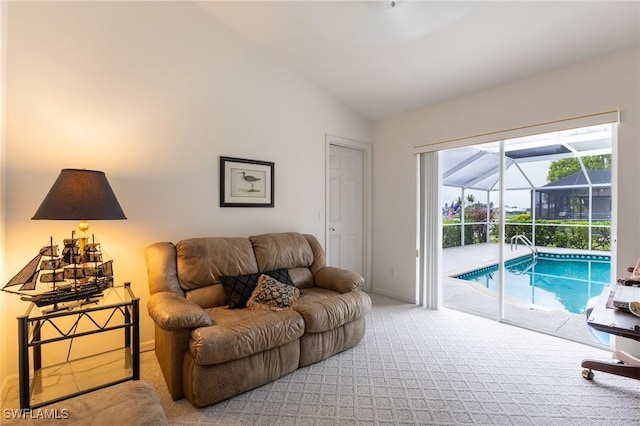 carpeted living room with baseboards, vaulted ceiling, and a sunroom
