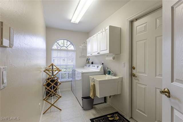 washroom featuring washer and dryer, baseboards, a sink, cabinet space, and light tile patterned floors
