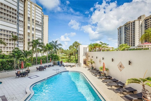 community pool with a patio area and fence