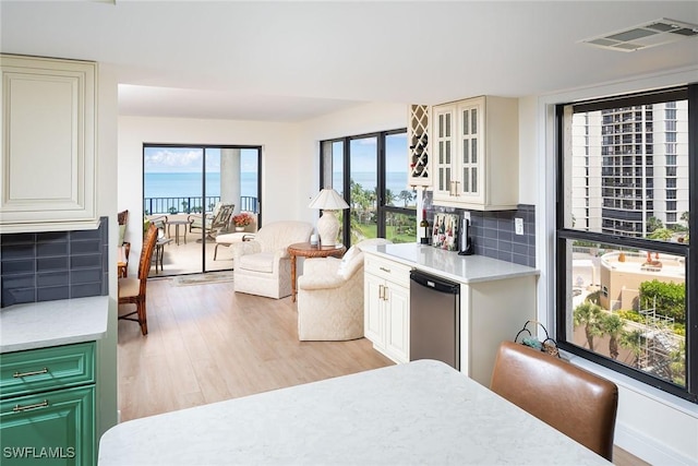 interior space featuring visible vents, decorative backsplash, fridge, light wood-type flooring, and light countertops