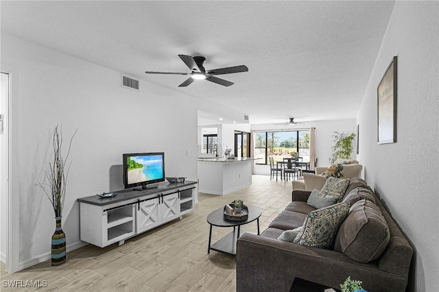living room featuring baseboards, ceiling fan, light wood-type flooring, and visible vents
