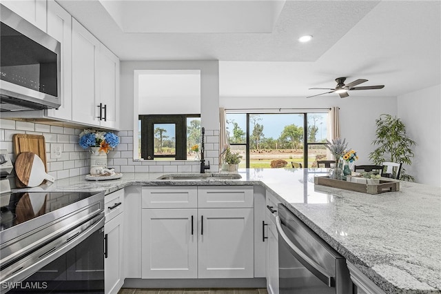 kitchen with stainless steel appliances, a ceiling fan, light stone counters, and tasteful backsplash