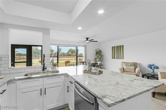 kitchen with light stone countertops, a sink, dishwasher, recessed lighting, and a ceiling fan