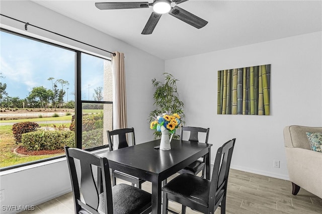 dining room featuring baseboards, a ceiling fan, and light wood finished floors