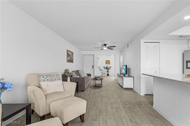 living room featuring a ceiling fan, baseboards, visible vents, and light wood-style floors