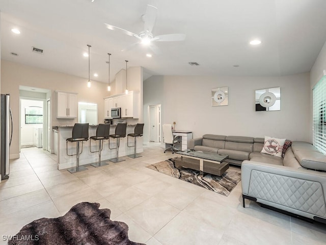 living area with visible vents, ceiling fan, light tile patterned floors, and vaulted ceiling