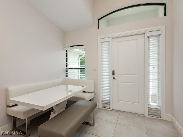 dining area with light tile patterned floors, baseboards, and vaulted ceiling