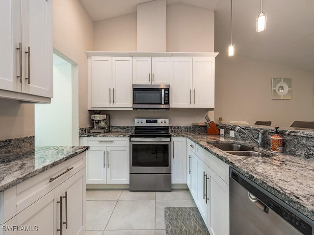 kitchen featuring vaulted ceiling, a sink, light tile patterned floors, white cabinets, and stainless steel appliances