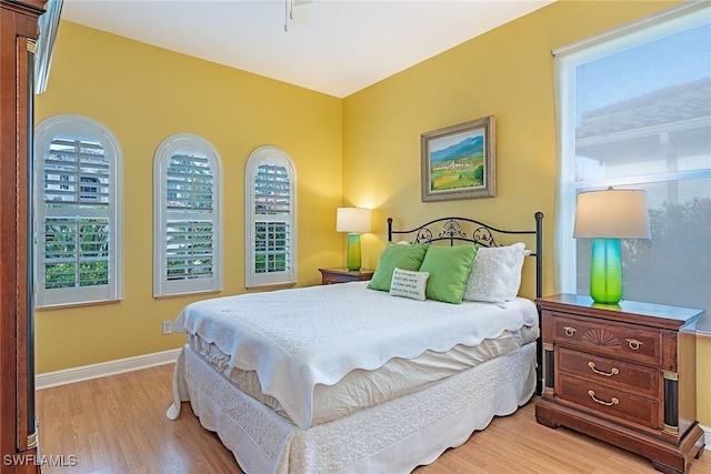 bedroom featuring light wood-style flooring, baseboards, and multiple windows