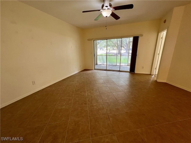 unfurnished room featuring dark tile patterned flooring, baseboards, and a ceiling fan