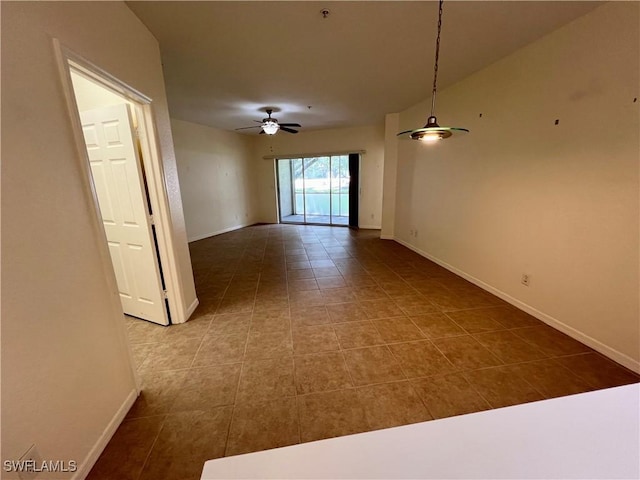 empty room featuring baseboards, a ceiling fan, and tile patterned floors