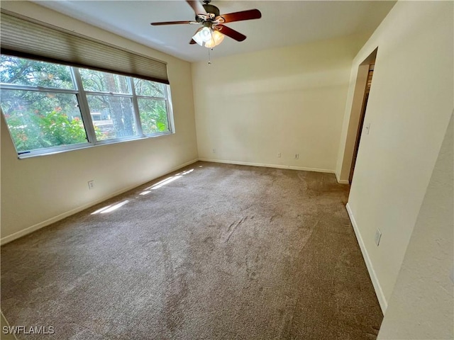 unfurnished room with a ceiling fan, baseboards, and carpet