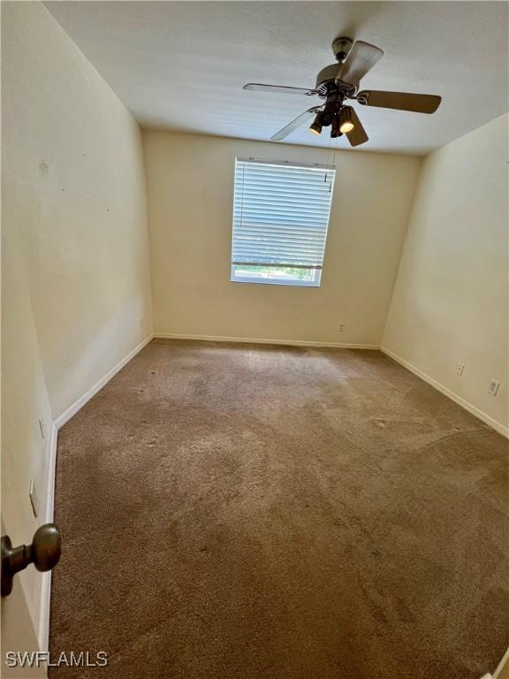 carpeted spare room featuring baseboards and ceiling fan