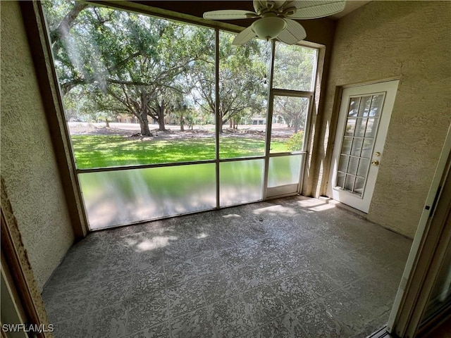 unfurnished sunroom with a ceiling fan and a water view