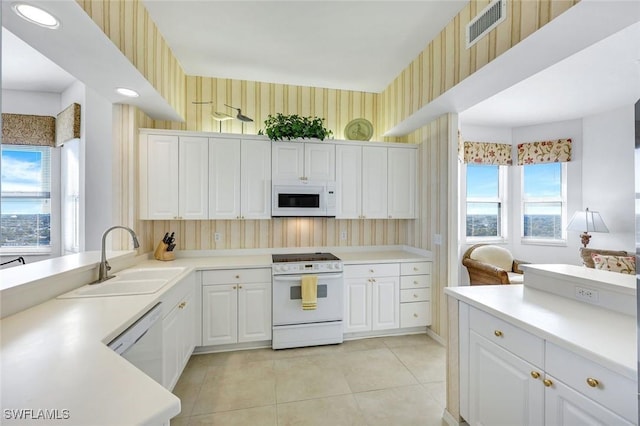 kitchen with visible vents, a sink, white appliances, and wallpapered walls