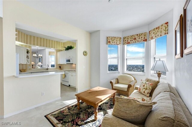 living area featuring baseboards, a notable chandelier, and a wealth of natural light