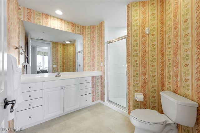 bathroom with vanity, a stall shower, toilet, and wallpapered walls