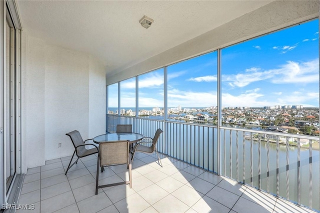 sunroom / solarium featuring a water view, tile patterned flooring, and a city view