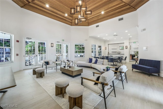 living room with wood ceiling, a towering ceiling, light wood finished floors, recessed lighting, and french doors