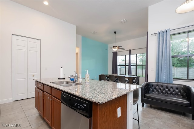 kitchen with ceiling fan, a kitchen bar, dishwasher, a sink, and light tile patterned floors