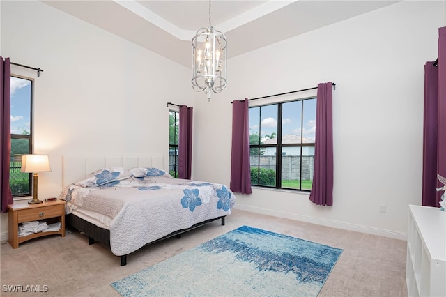 carpeted bedroom featuring baseboards, a chandelier, and a high ceiling