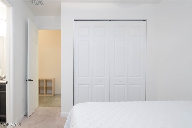 bedroom featuring baseboards, a closet, light colored carpet, and visible vents