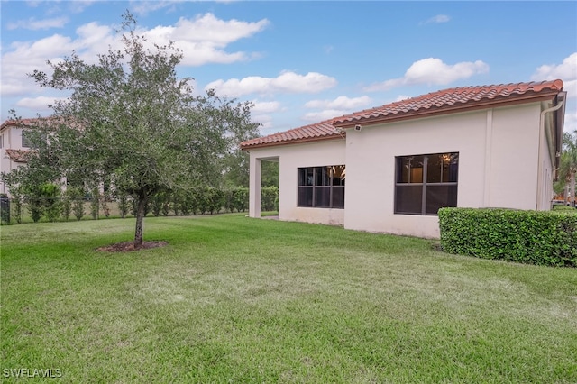 exterior space featuring a lawn, fence, stucco siding, and a tile roof