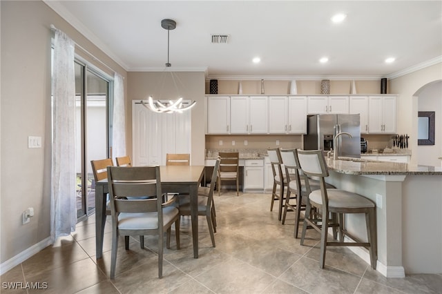interior space with ornamental molding, white cabinetry, light stone countertops, and stainless steel refrigerator with ice dispenser