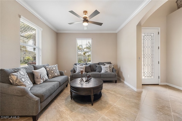 living room featuring ornamental molding, ceiling fan, arched walkways, light tile patterned floors, and baseboards