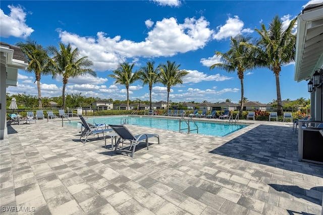community pool with a patio area and fence