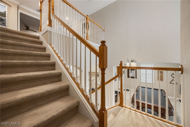 stairs featuring ceiling fan and ornamental molding