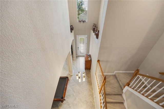 stairs featuring a high ceiling, baseboards, arched walkways, and a textured wall