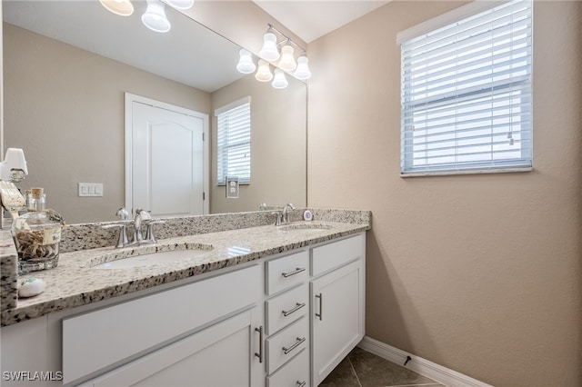 bathroom featuring baseboards, tile patterned flooring, double vanity, and a sink