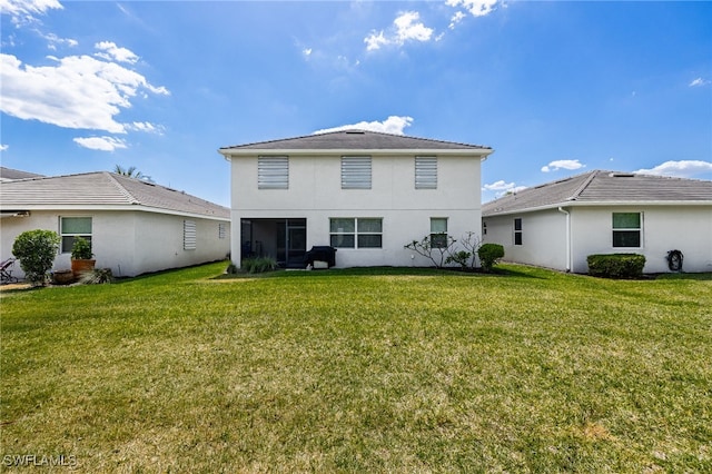 rear view of house featuring a lawn and stucco siding