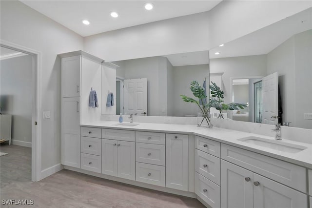 full bathroom featuring double vanity, a sink, baseboards, and recessed lighting