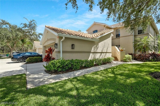 view of side of home featuring a lawn, a garage, stucco siding, and a tile roof