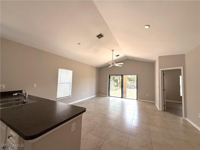 kitchen featuring light tile patterned flooring, dark countertops, ceiling fan, a sink, and vaulted ceiling