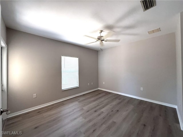 empty room featuring baseboards, visible vents, a ceiling fan, and dark wood-type flooring